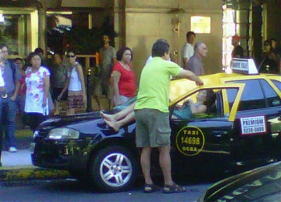In this cell phone photo provided by Infobae.com received via Twitter from @denisitabaires, a woman lies over a taxi after falling from the 23 floor of a hotel in downtown Buenos Aires, Argentina, on Monday. The seriously injured woman was taken to a hospital while the taxi driver managed to get out of the car before the impact.